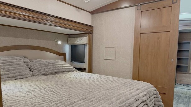 Un dormitorio con cama, televisor y armario.