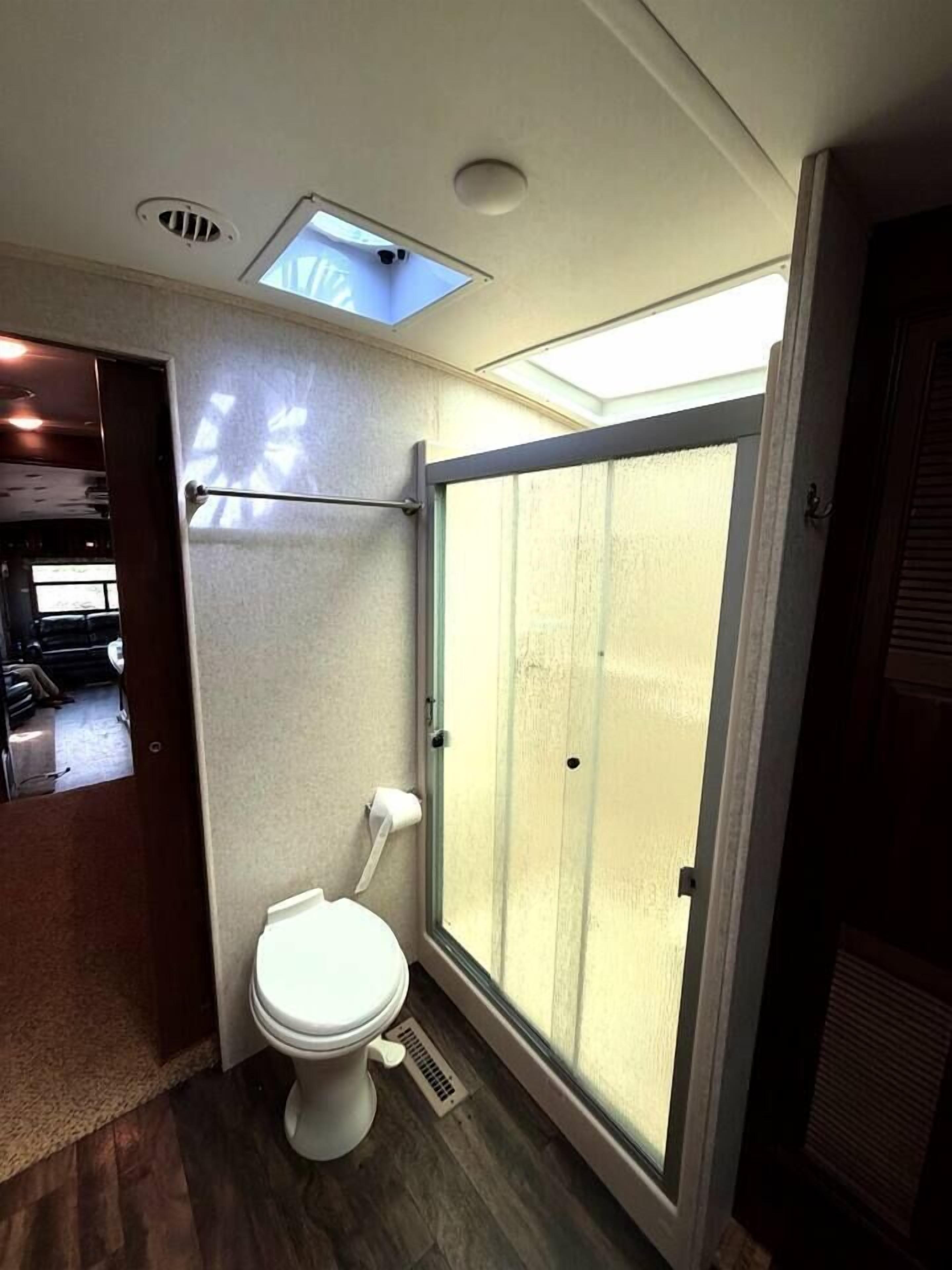 Une petite salle de bain comprenant des toilettes, un espace douche et un puits de lumière.