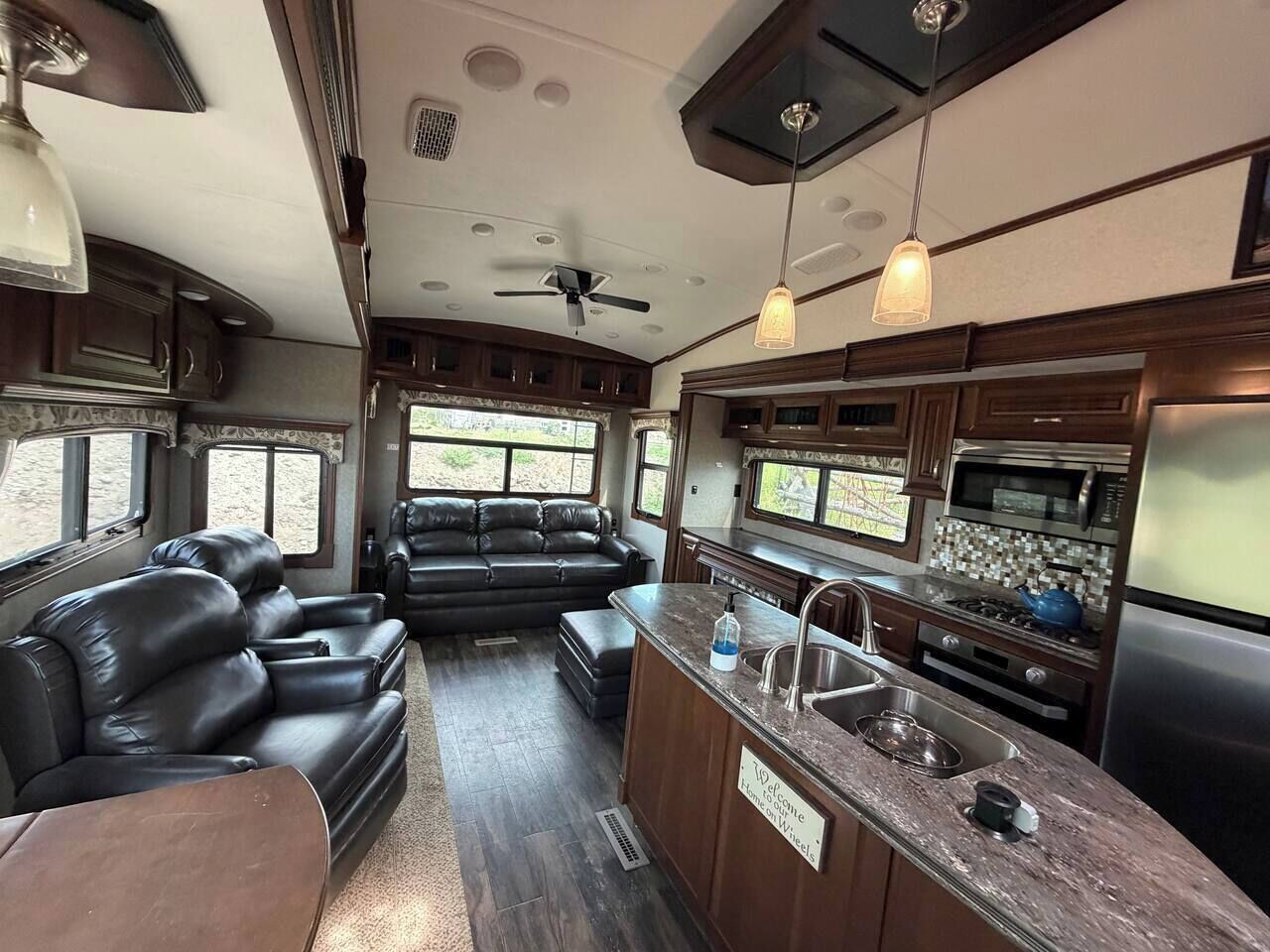 Een compact RV-interieur met een kitchenette, zithoek en plafondventilator.