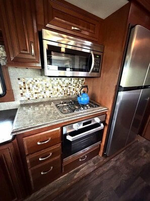 A compact kitchen with a microwave, oven, and refrigerator.