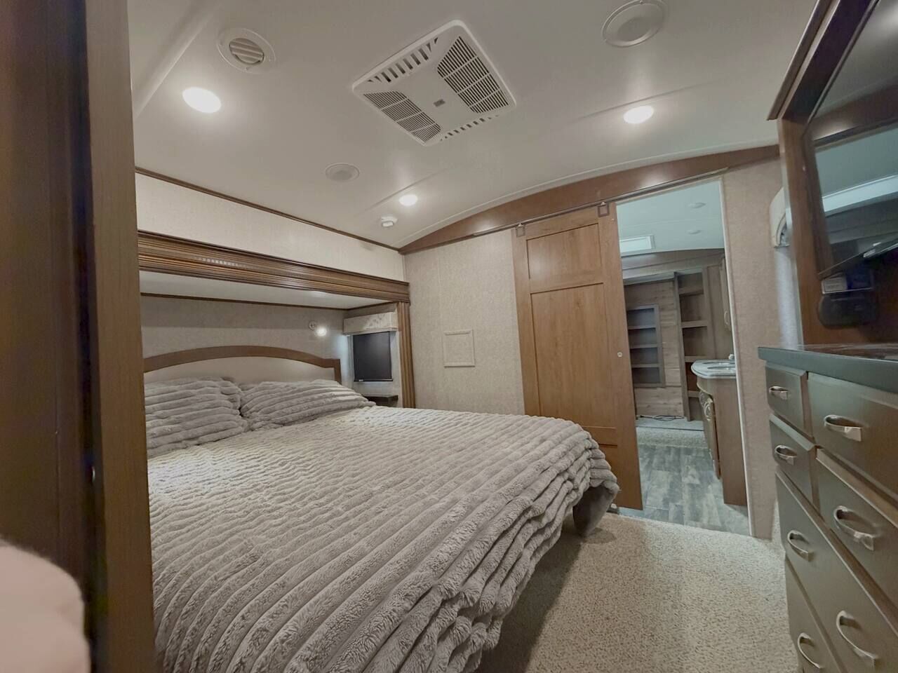 Een slaapkamer met een bed, een dressoir, een televisie en een kledingkast.