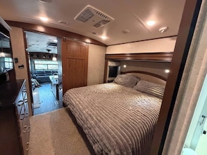 Een slaapkamer met een bed, een hoofdeinde en een raam.