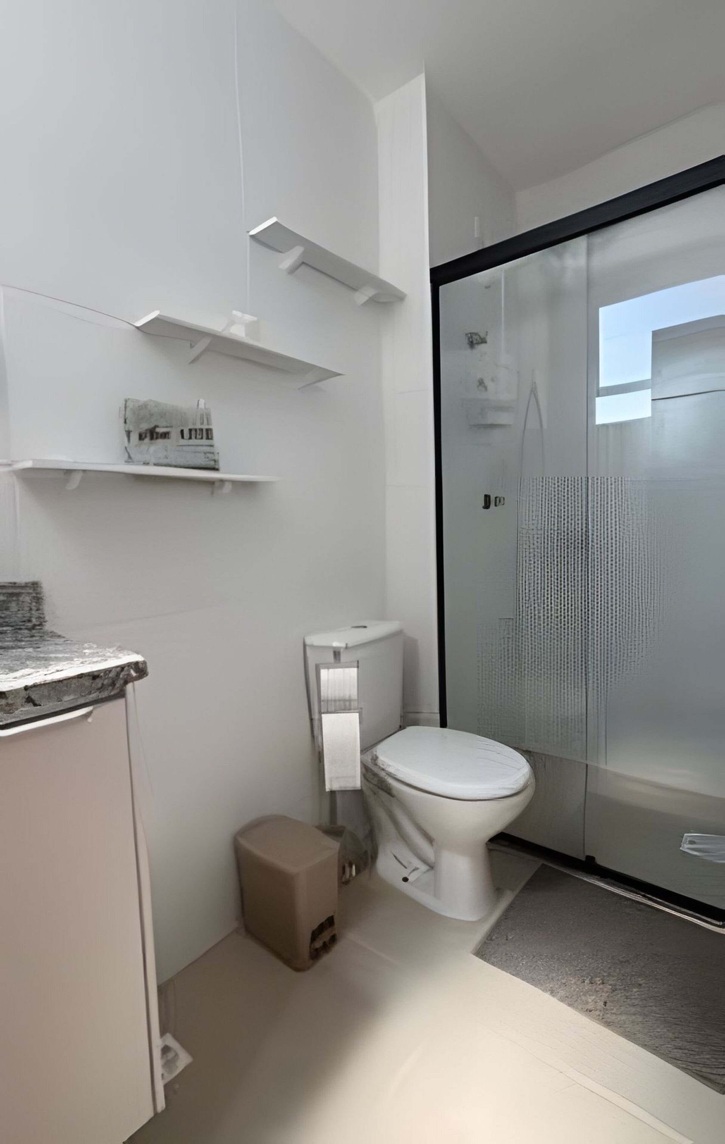 Une salle de bain moderne comprenant des toilettes, un espace douche et un petit meuble de rangement.