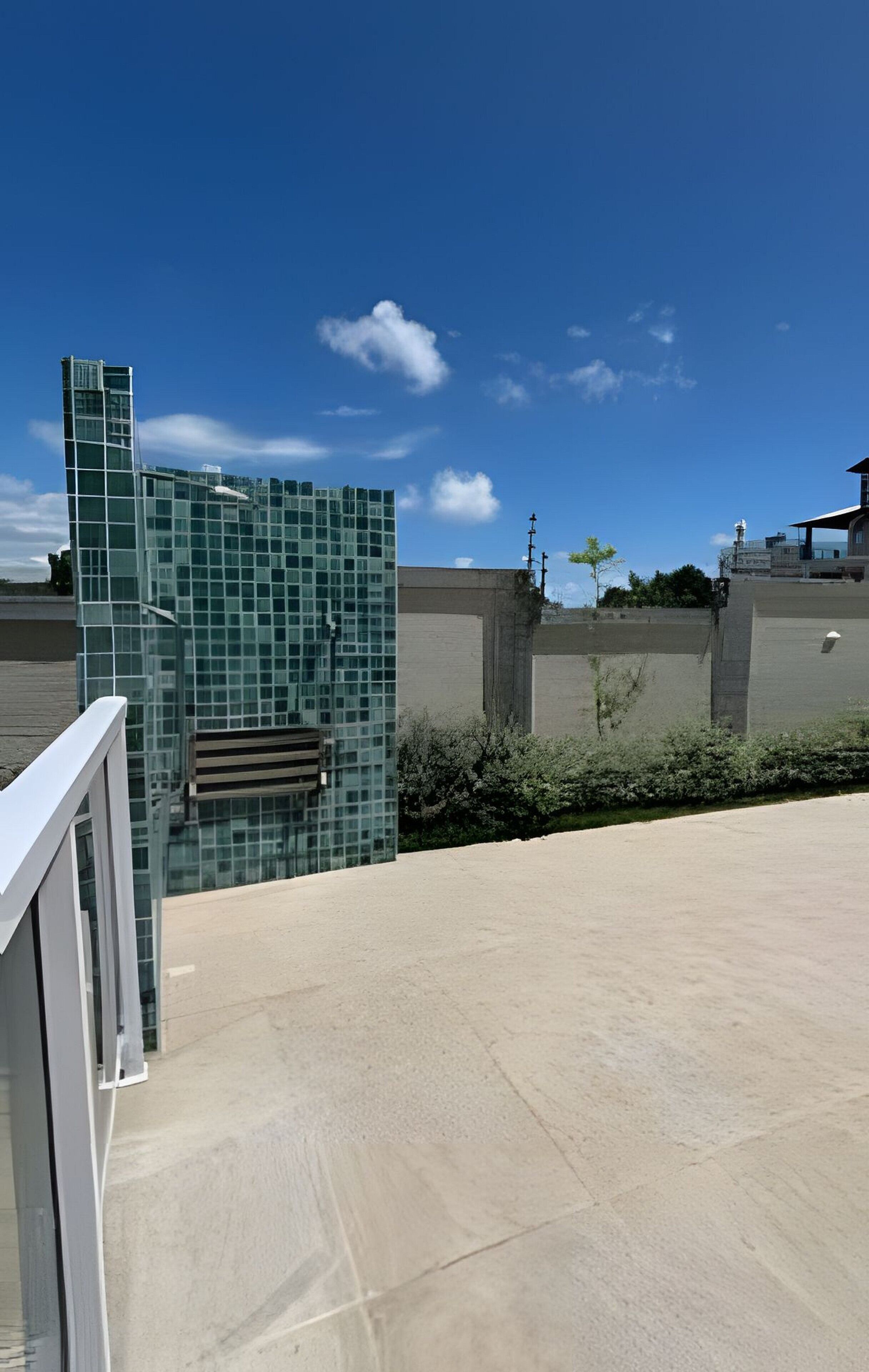 Ein modernes Gebäude mit Glasfassade, einer Betonwand und blauem Himmel.