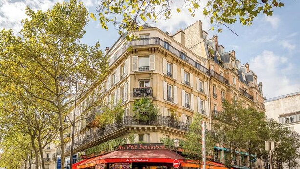 Un edifici als angles amb un restaurant anomenat 'Au Petit Boulevard' a la planta baixa.