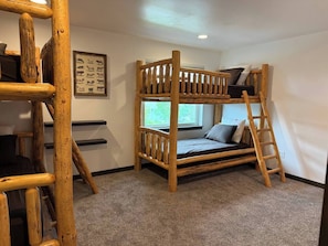 Una cama litera con escalera, un cuadro en la pared y una ventana con vistas.