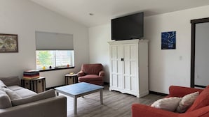 A living room with a sofa, armchair, coffee table, TV, cabinet, and artwork. - 4 Min to Airport • Family Retreat Sleeps 10 (Belgrade)