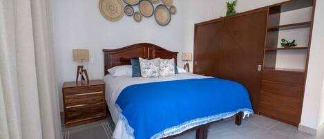 Un dormitorio con cama, mesitas de noche, armario y decoración en la pared.