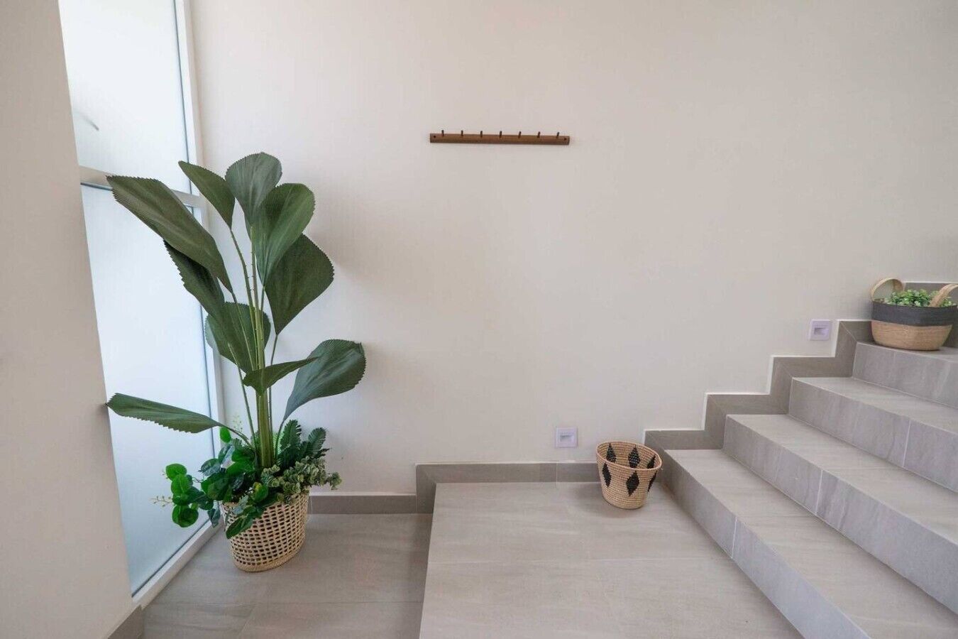A staircase with a light-colored floor, a potted plant, and a woven basket on the landing.