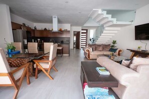 Ein modernes Wohnzimmer mit einer Couch, einem Couchtisch und einem Essbereich mit Stühlen.