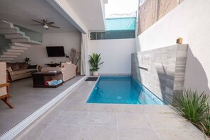 Ein modernes Interieur mit Pool, Treppe und Flachbildfernseher.
