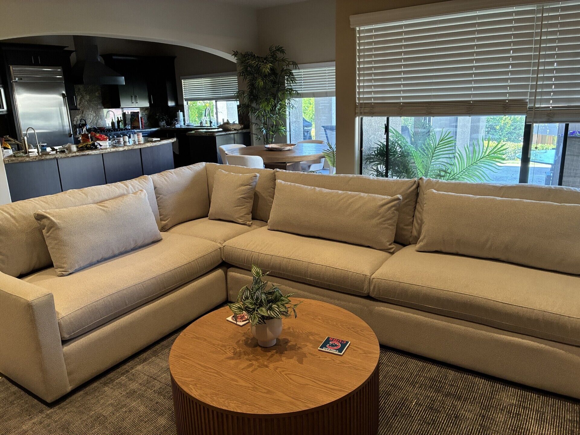 A modern living room with a sectional sofa, a coffee table, and a kitchen in the background.