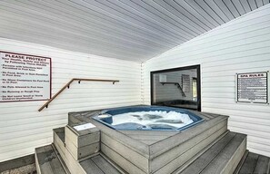 Ein Wellnessbereich mit Whirlpool, Holzstufen und zwei Informationsschildern an den Wänden.