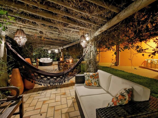 Un patio exterior con una hamaca, zona de estar e iluminación ambiental.