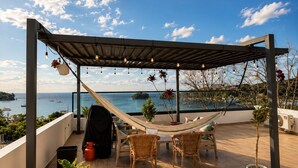 Una terrazza sul tetto con un'amaca, mobili in vimini e piante in vaso.