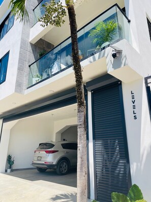 A modern building with a car parked in a covered parking area. - LEVEL 2, Lovely 2-bedroom apartment with AC steps to malecon in Santa Barbara (Santa Barbara)
