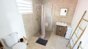 A bathroom with a shower, toilet, sink, and a small wooden cabinet. - Ti Kaz Romance, calm and relaxation (Sainte-Suzanne)