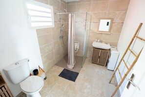 Un baño con ducha, inodoro, lavamanos y un pequeño armario de madera.