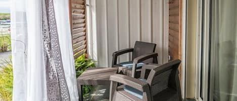 A balcony with wicker furniture, a sliding glass door, and a view of the outdoors.