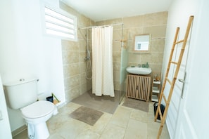 A bathroom with a toilet, shower, and sink.