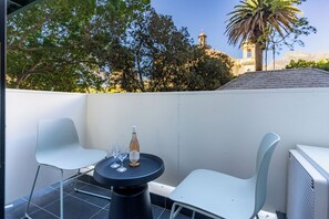 Eine Terrasse mit Tisch, zwei Stühlen, einer Flasche und Gläsern.