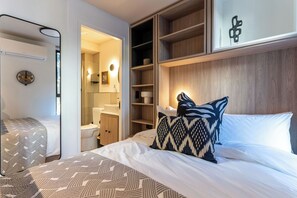 Habitación de hotel con cama, mesita de noche, armario, baño y vistas al exterior.