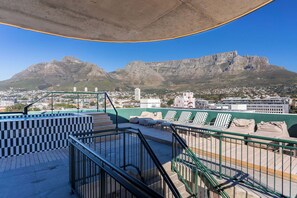 Terraço no telhado com vista para montanhas e a cidade.