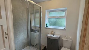 Un bany amb dutxa amb envàs de vidre, un lavabo i un vàter.