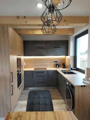 A modern kitchen with wooden cabinets, a black countertop, and a built-in oven.