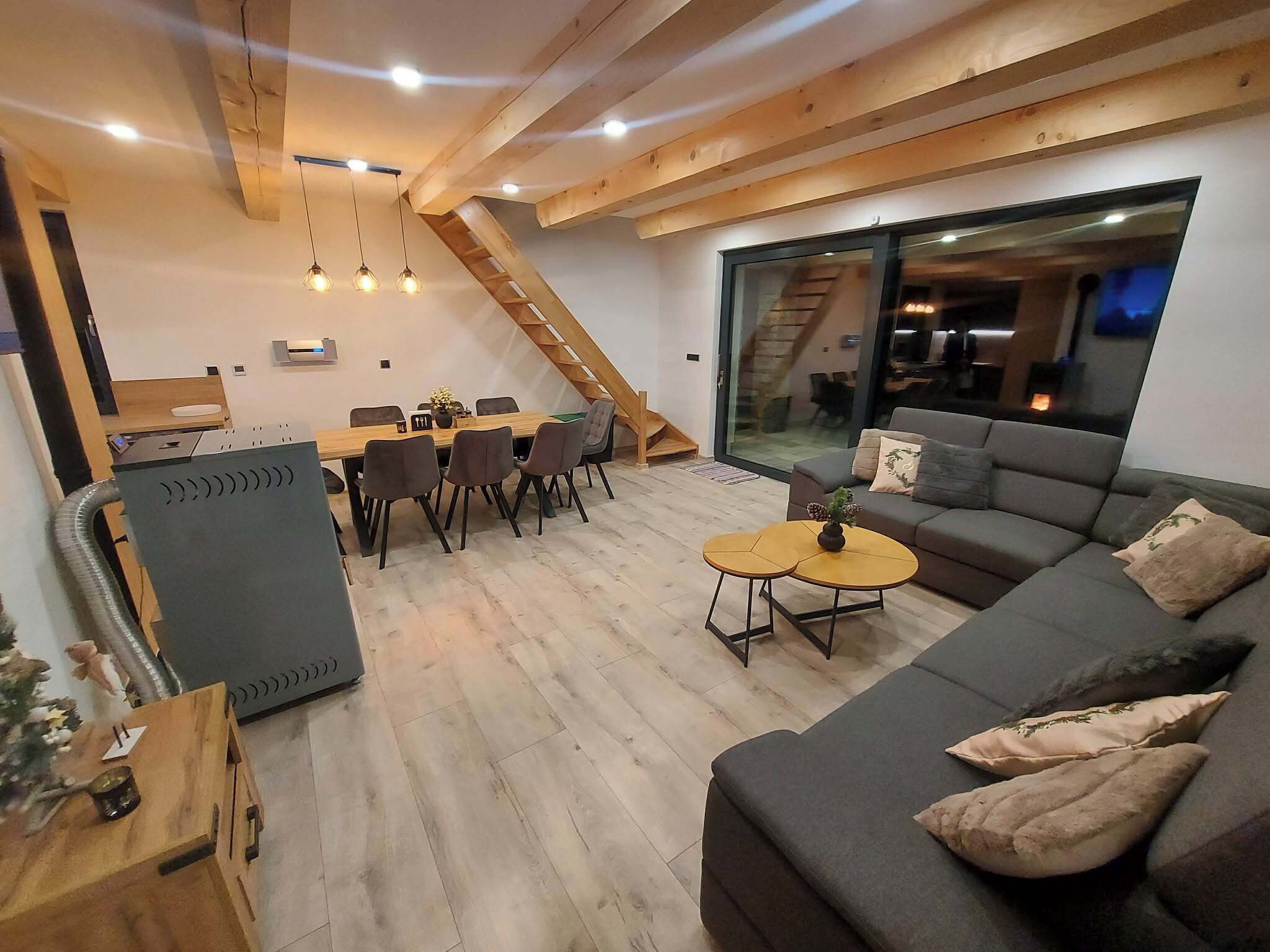 A modern living space with a dining area, a sofa, and a staircase.