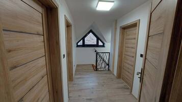 A hallway with wooden doors and a sloped ceiling with a skylight.