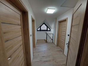 A hallway with wooden doors and a sloped ceiling with a skylight.