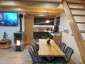 A modern kitchen with a wooden table and chairs, a TV, and a fireplace.