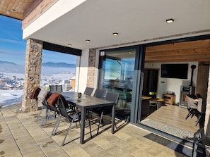 An outdoor dining area with a stone column, a table, and chairs.
