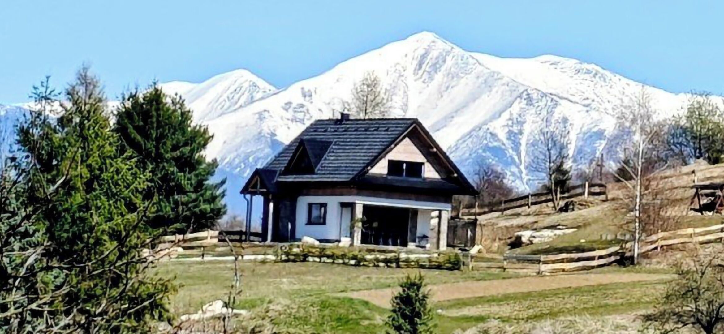 A house with a sloped roof, a covered porch, and a mountain backdrop.