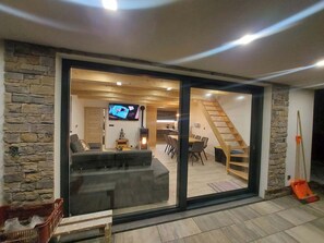 Ein modernes Interieur mit einer Steinsäule, einer Couch, einem Fernseher, einer Treppe und einem Essbereich.
