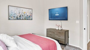 A bedroom with a bed, a dresser, a painting, and a TV on the wall. - Melon Ridge Getaway/King Suite/TVs in all rooms (Rio Rancho)