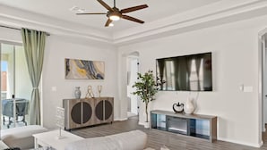 A modern living room with a sofa, a coffee table, a TV, and a ceiling fan. - Melon Ridge Getaway/King Suite/TVs in all rooms (Rio Rancho)