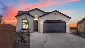 A residential house with a garage, a driveway, and a landscaped front yard. - Melon Ridge Getaway/King Suite/TVs in all rooms (Rio Rancho)