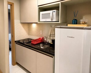 Eine Küche mit einem weißen Kühlschrank, einer Mikrowelle, einem Spülbecken und einem roten Korb.