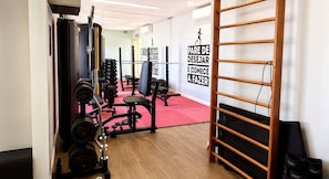 A gym with weightlifting equipment, a red carpet, and motivational wall art. - Costa Azul 403 (Salvador)