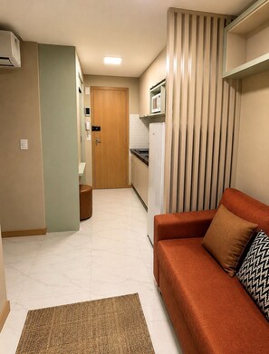 A compact living space with a kitchenette, a sofa, and a patterned rug. - Costa Azul 403 (Salvador)