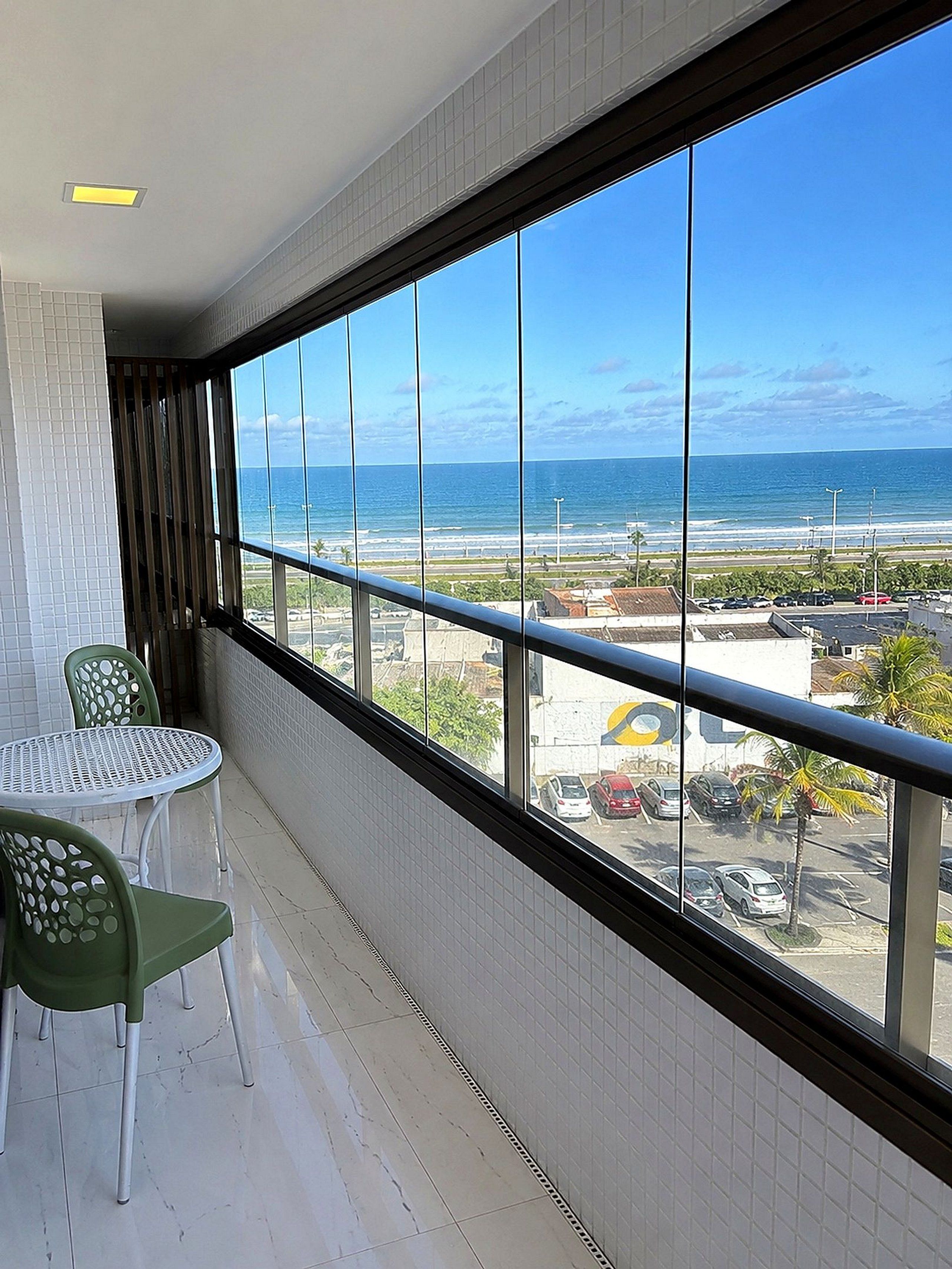 A balcony with a view of the ocean, a table, and two chairs.