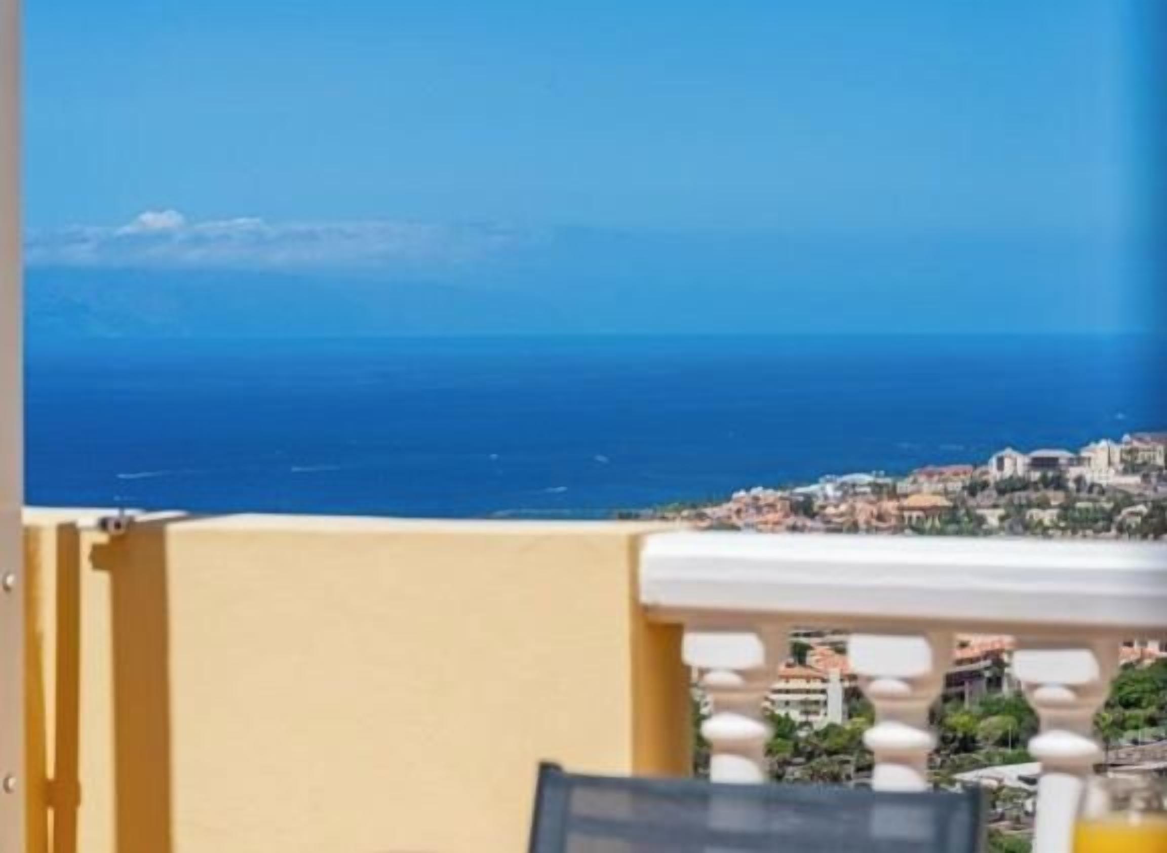 Un balcón con vista al mar y a un pueblo costero.