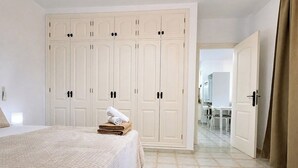A bedroom with a bed, a wardrobe, and a bathroom visible through an open door.