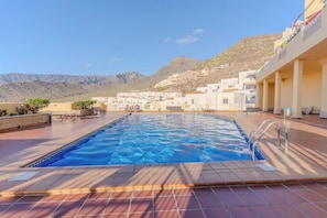 A swimming pool with a view of a hillside town. - Apartment with terrace & views in Adeje (Torviscas Alto)