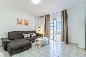Ein Wohnzimmer mit einer Couch, einem Couchtisch und einem großen Fenster.