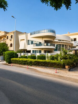 A multi-story building with a curved facade, large windows, and a balcony on the upper level. - Family Room in a Luxury Villa (New Cairo)