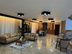 Amplia sala de estar con un conjunto de sofás, una mesa de centro y una mesa de comedor con sillas.
