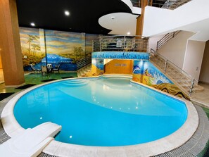 An indoor swimming pool with a mural of a landscape and underwater scene. - Family Room in a Luxury Villa (New Cairo)